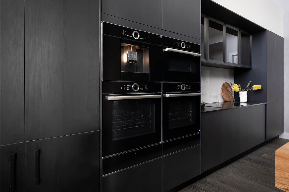 The Block 2021 Josh and Luke's kitchen with dark woodgrain cabinetry and black appliances