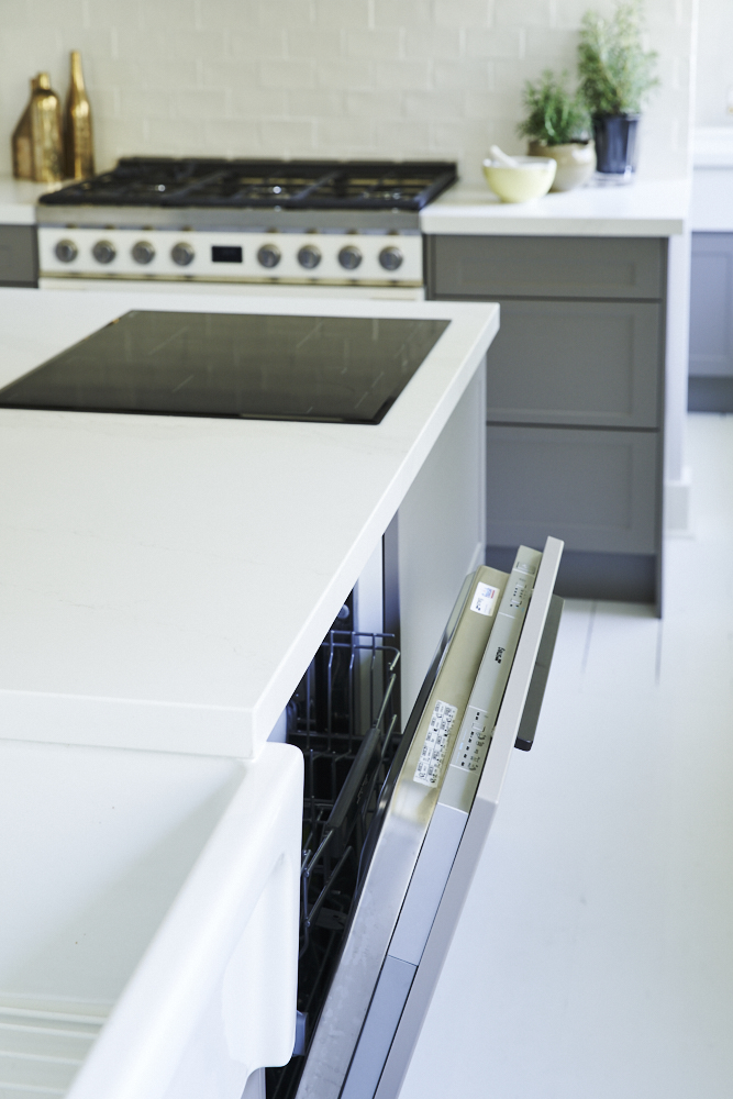 Elegant shaker style kitchen with grey cabinetry, white countertops and a large center island