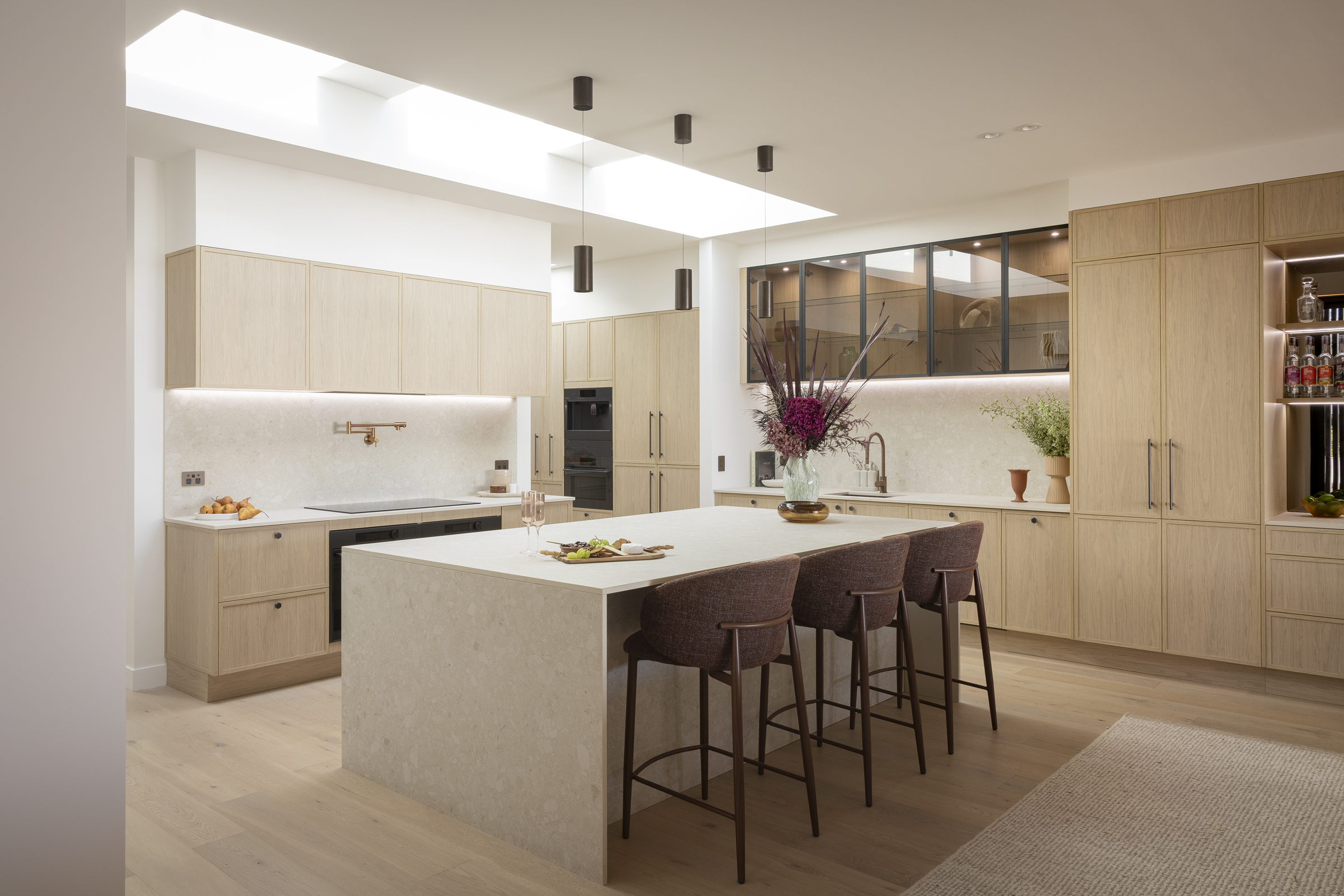 MA020 Kitchen with warm oak-toned cabinetry, stone-look island and glass-front wall cabinets
