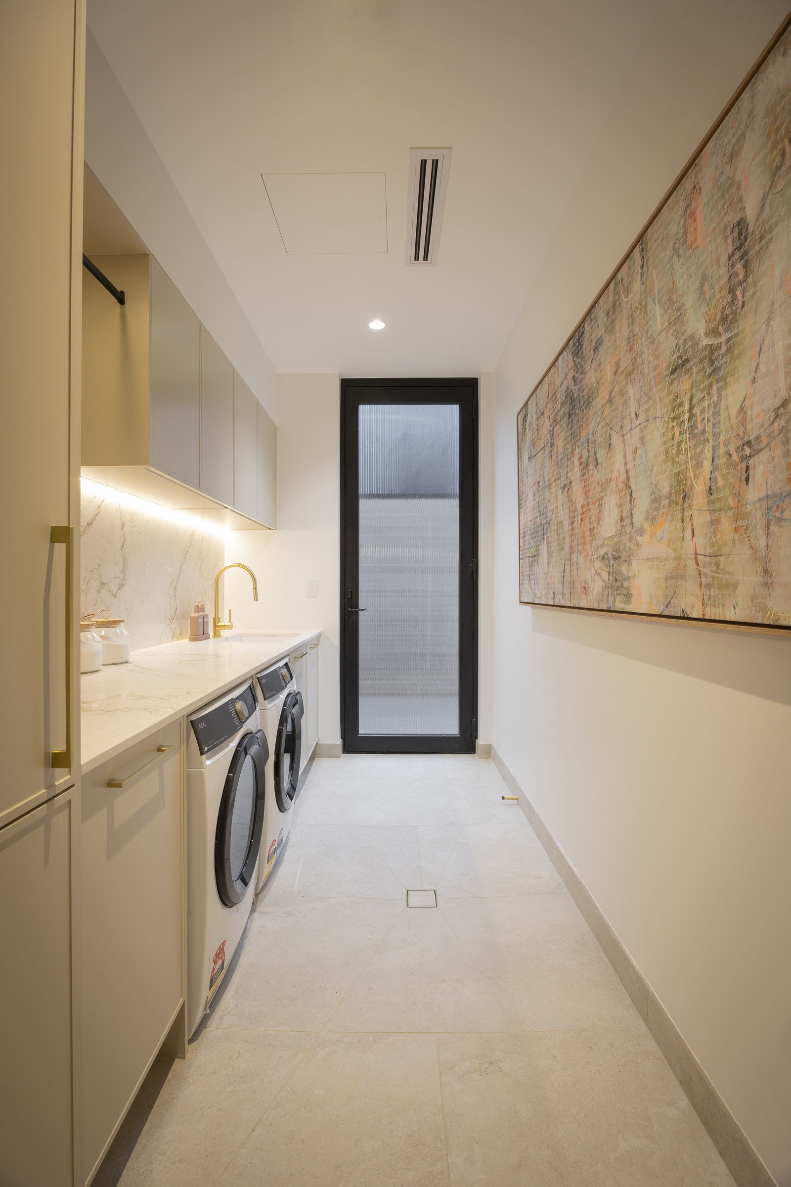 Galley small laundry with grey cabinets, strip LED lighting, stone benchtops