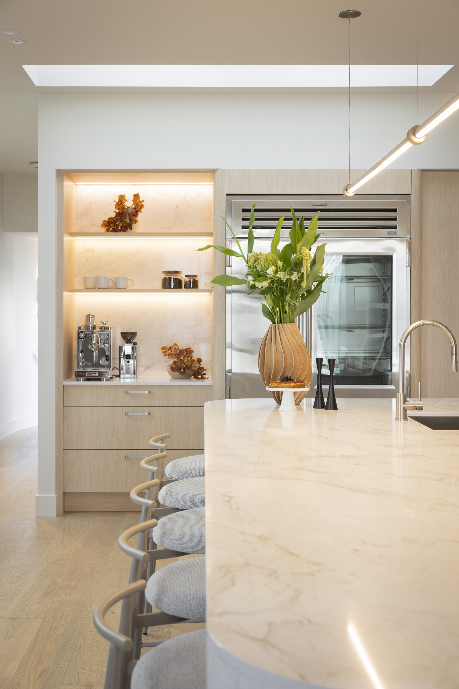 Curved Eclos Landr island benchtop with timber-look cabinetry and lit open shelving