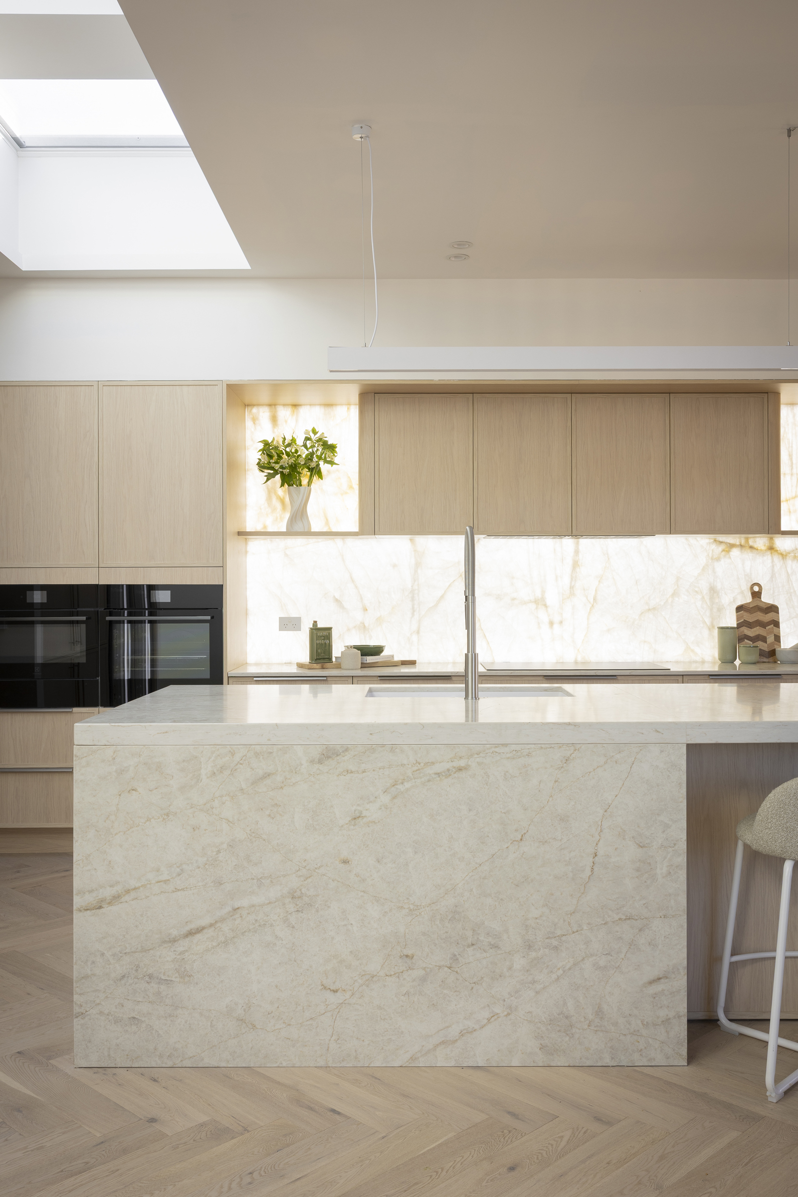 Eclos Tajnar waterfall island in front of a backlit natural stone splashback