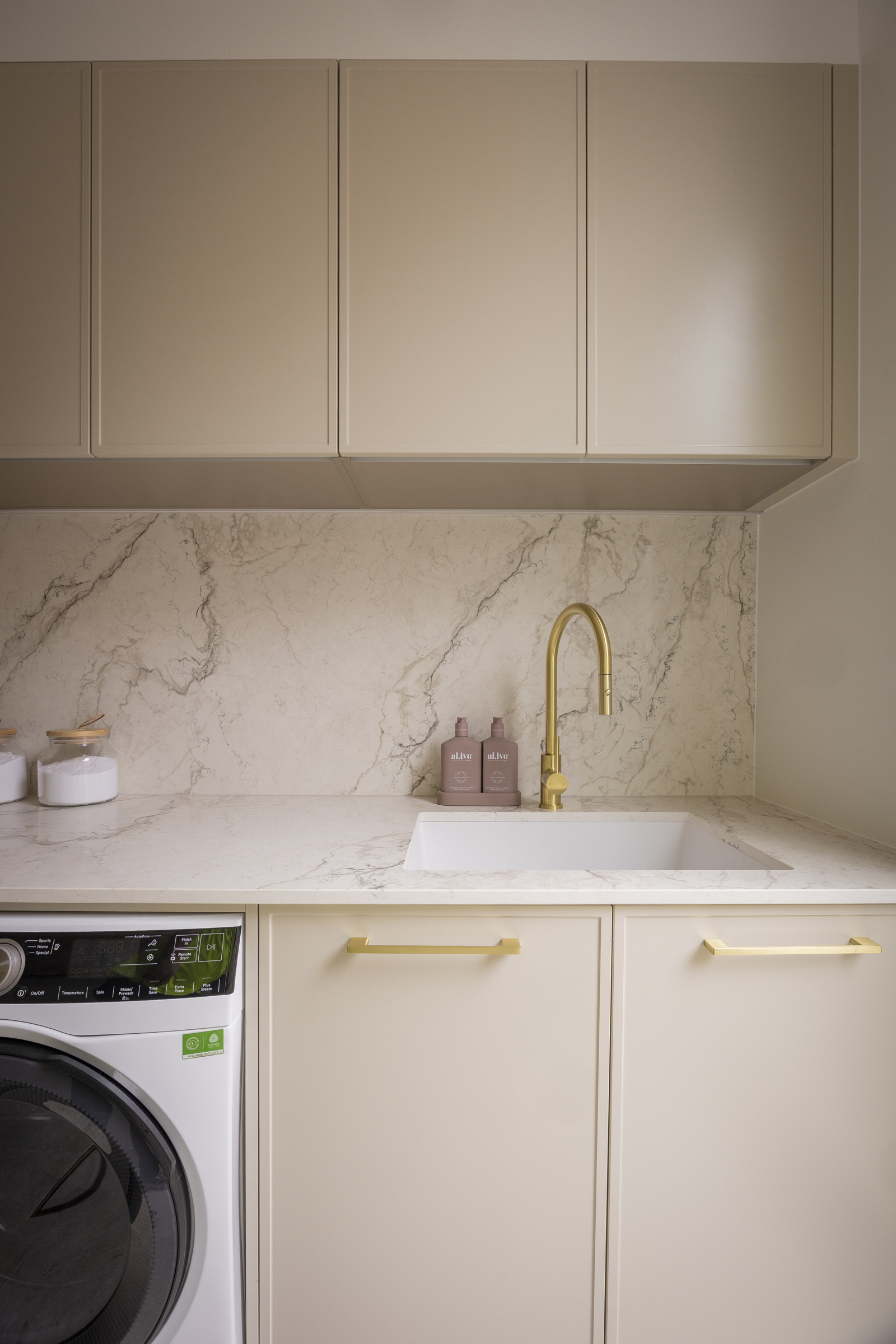 Laundry with Eclos Wondr benchtop and splashback, Shaker-style cabinetry and brass tapware
